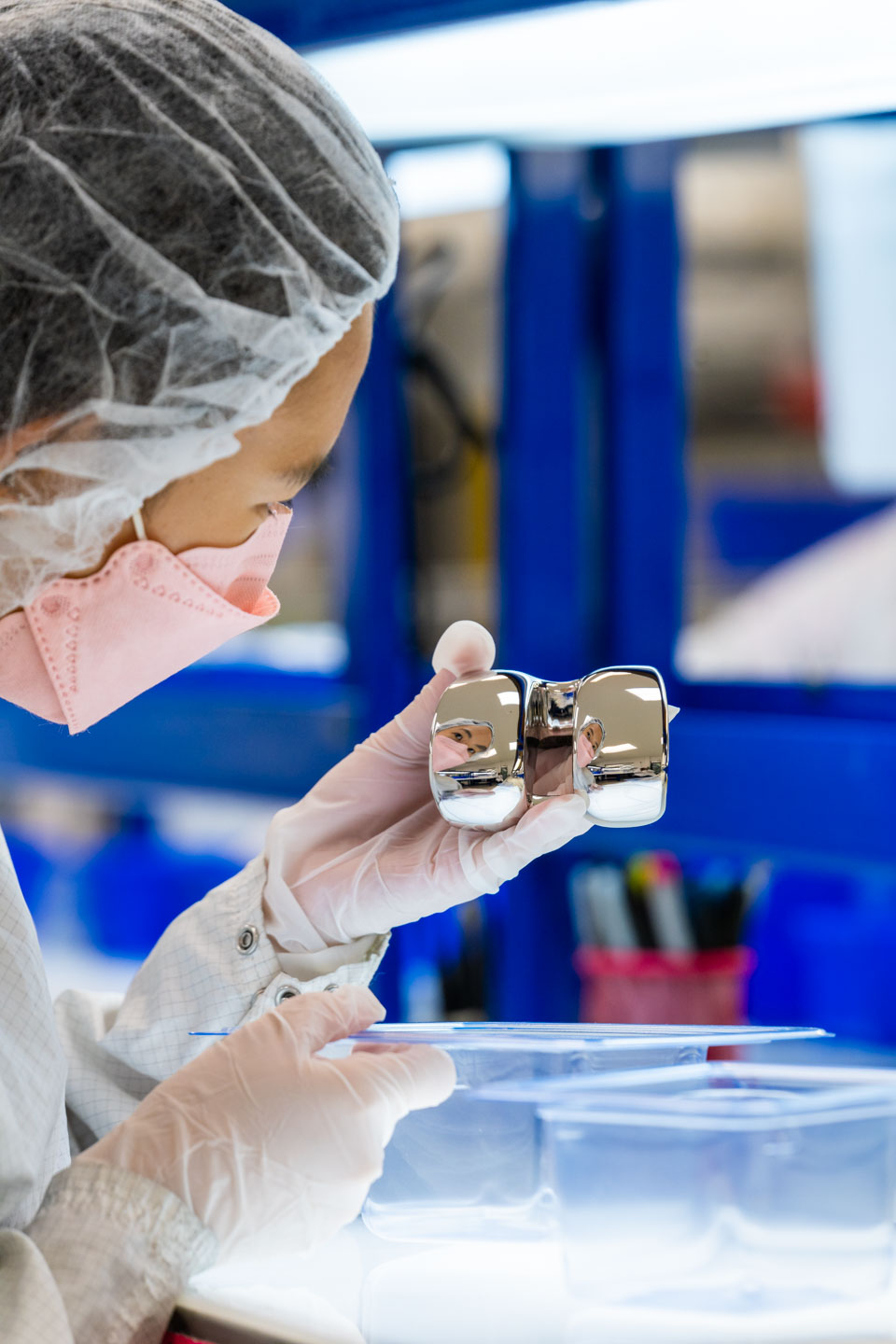 Sara Adachi in the Life Science Outsourcing cleanroom holding an orthopedic implant