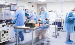 A cleanroom with technicians in protective gear working on packaging reagents.