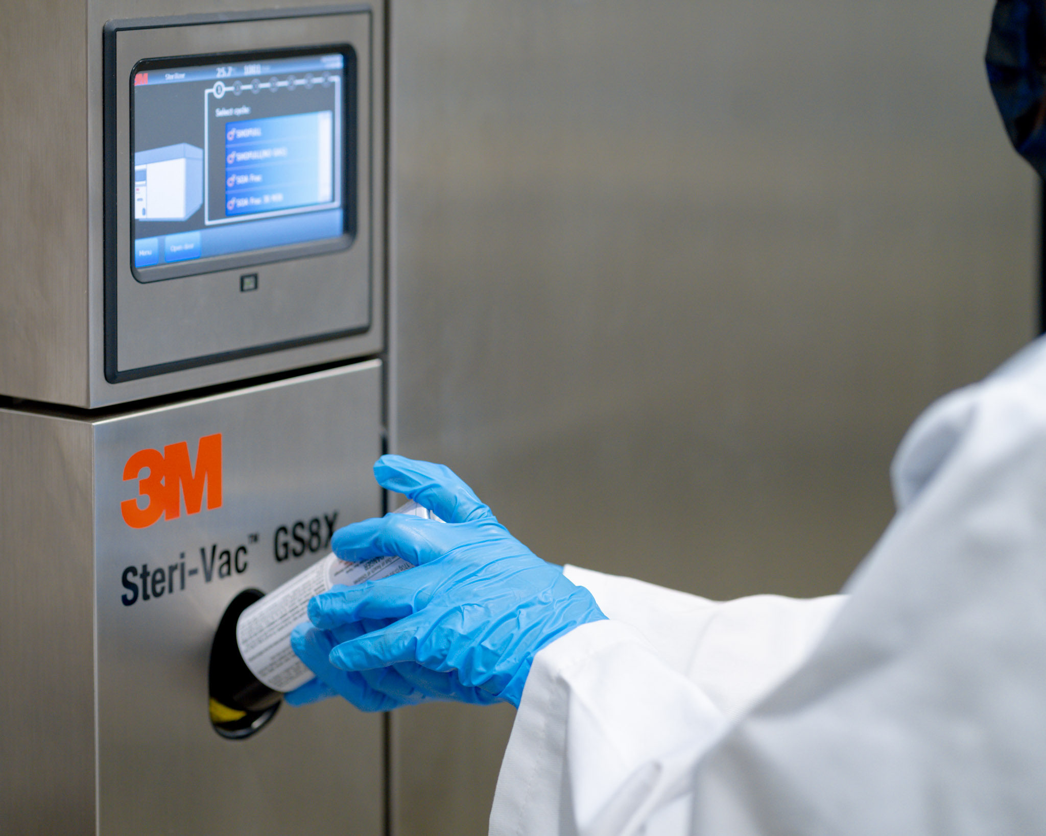 Close-up of a gloved hand placing a EtO sterilization canister into a 3M Steri-Vac GS8X system.