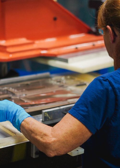 A technician working on a thermoforming machine, shaping packaging trays with precision in a clean manufacturing environment.