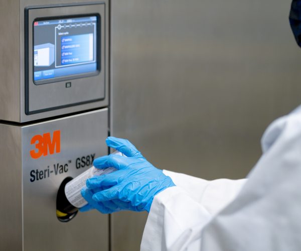 Close-up of a gloved hand placing a EtO sterilization canister into a 3M Steri-Vac GS8X system.