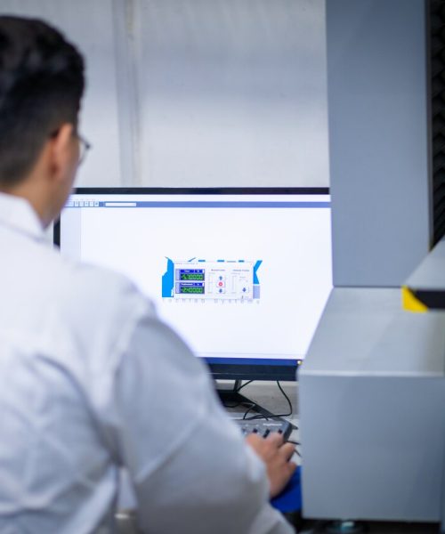 Technician reviewing accelerated aging test data on a computer in a controlled laboratory environment.