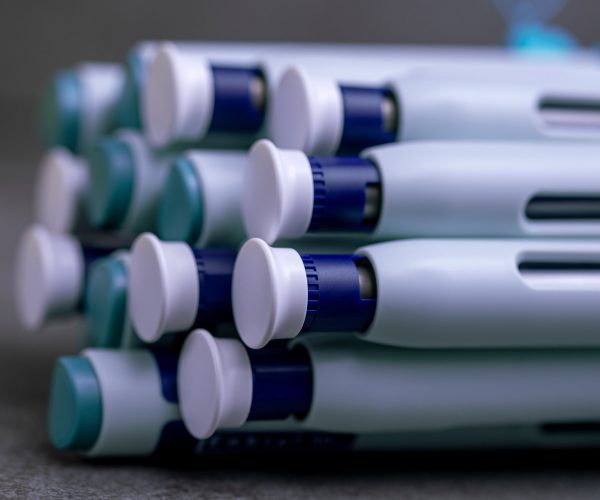 Autoinjectors for Drug Delivery – Precision-Engineered Medical Devices Close-up of stacked autoinjector drug delivery pens, showcasing advanced design and precision manufacturing.
