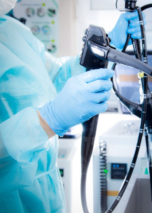 Endoscope Handling in Clinical Setting – Gastroenterology Device Technician in PPE handling a flexible endoscope in a sterile environment, representing gastroenterology device care and processing.