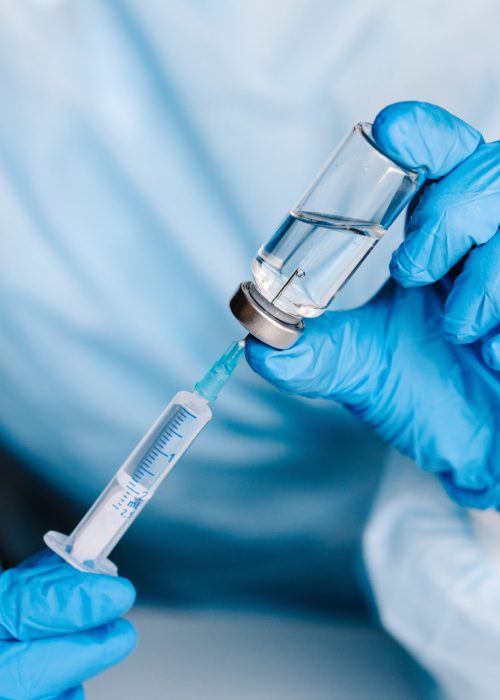 In-House Steam Sterilization for Vials and Syringes – CDER Certified Gloved technician drawing liquid from sterile vial into syringe in cleanroom environment