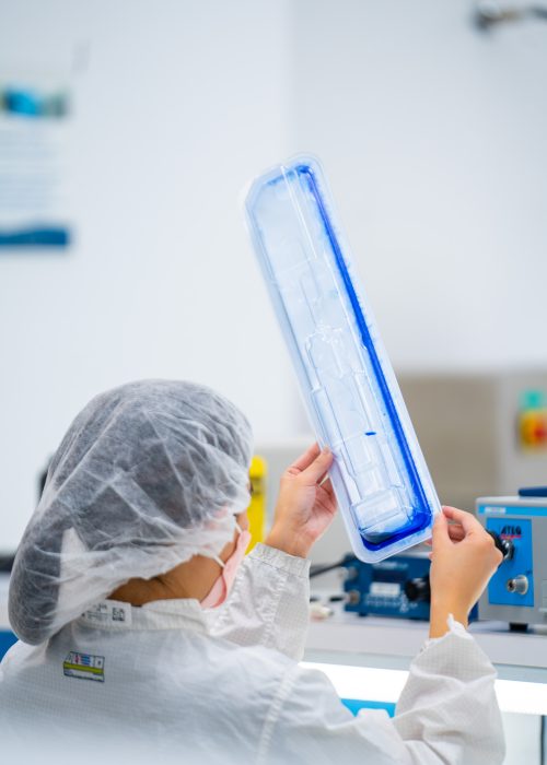 Leak Dye Testing for Medical Packaging – ASTM F1929 A laboratory technician in a cleanroom inspecting a medical device tray for seal integrity using blue dye penetration testing.