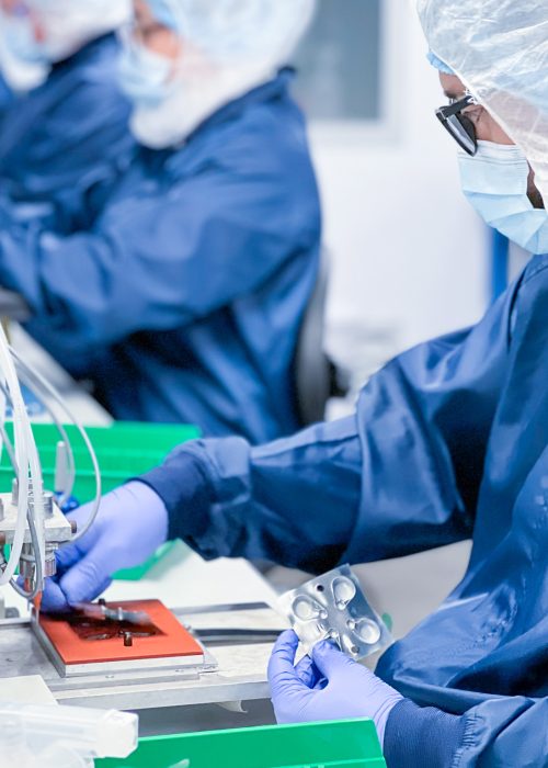 Technician assembling a medical device in a cleanroom environment, wearing protective gear to ensure sterility and compliance with FDA and ISO 13485 standards.