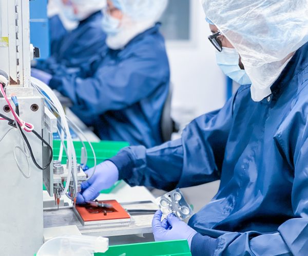 Medical Device Assembly in Cleanroom – Precision Manufacturing Technician assembling a medical device in a cleanroom environment, wearing protective gear to ensure sterility and compliance with FDA and ISO 13485 standards.