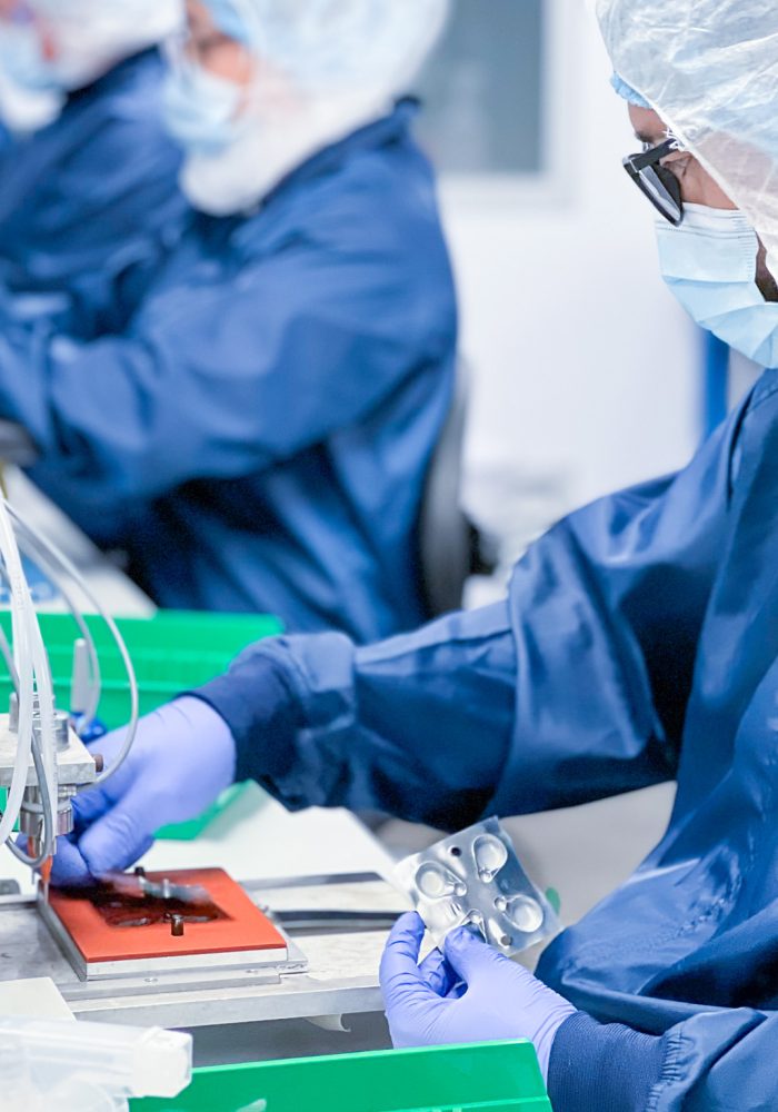 Technician assembling a medical device in a cleanroom environment, wearing protective gear to ensure sterility and compliance with FDA and ISO 13485 standards.