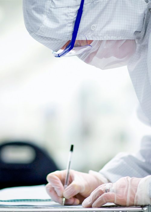 LSO Medical Device Assembly Quality Supervisor meticulously reviewing documentation in a pristine cleanroom to ensure optimal production standards.