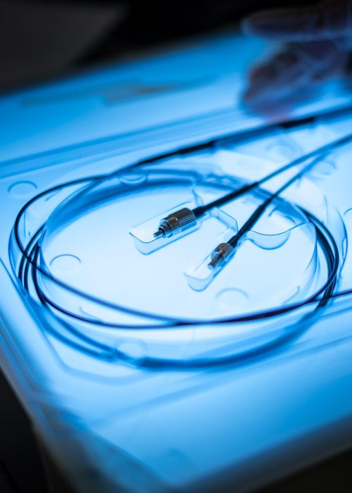 Sterile Coiled Guidewire in Medical Packaging – Cardiovascular Device Close-up of a coiled cardiovascular guidewire sealed in sterile packaging under blue inspection light.