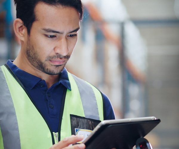 Warehouse Worker Using Digital Inventory Management Warehouse worker in a safety vest using a tablet and barcode scanner for inventory tracking