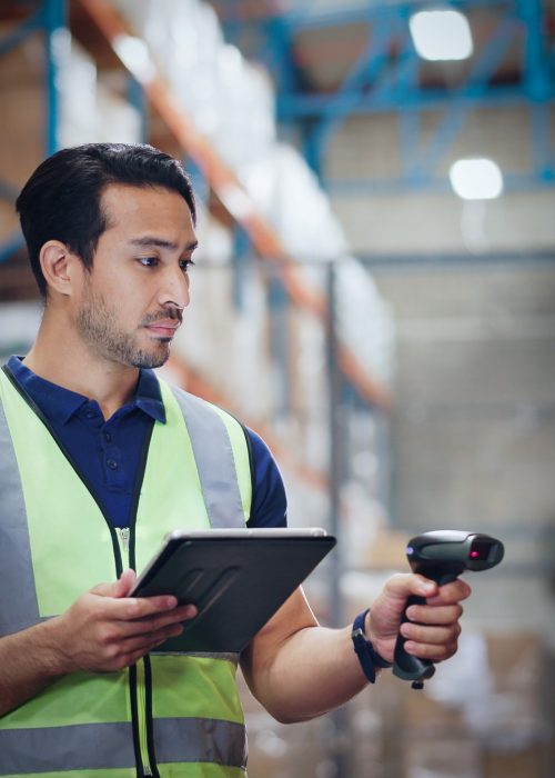 Warehouse Worker Using Digital Inventory Management Warehouse worker in a safety vest using a tablet and barcode scanner for inventory tracking
