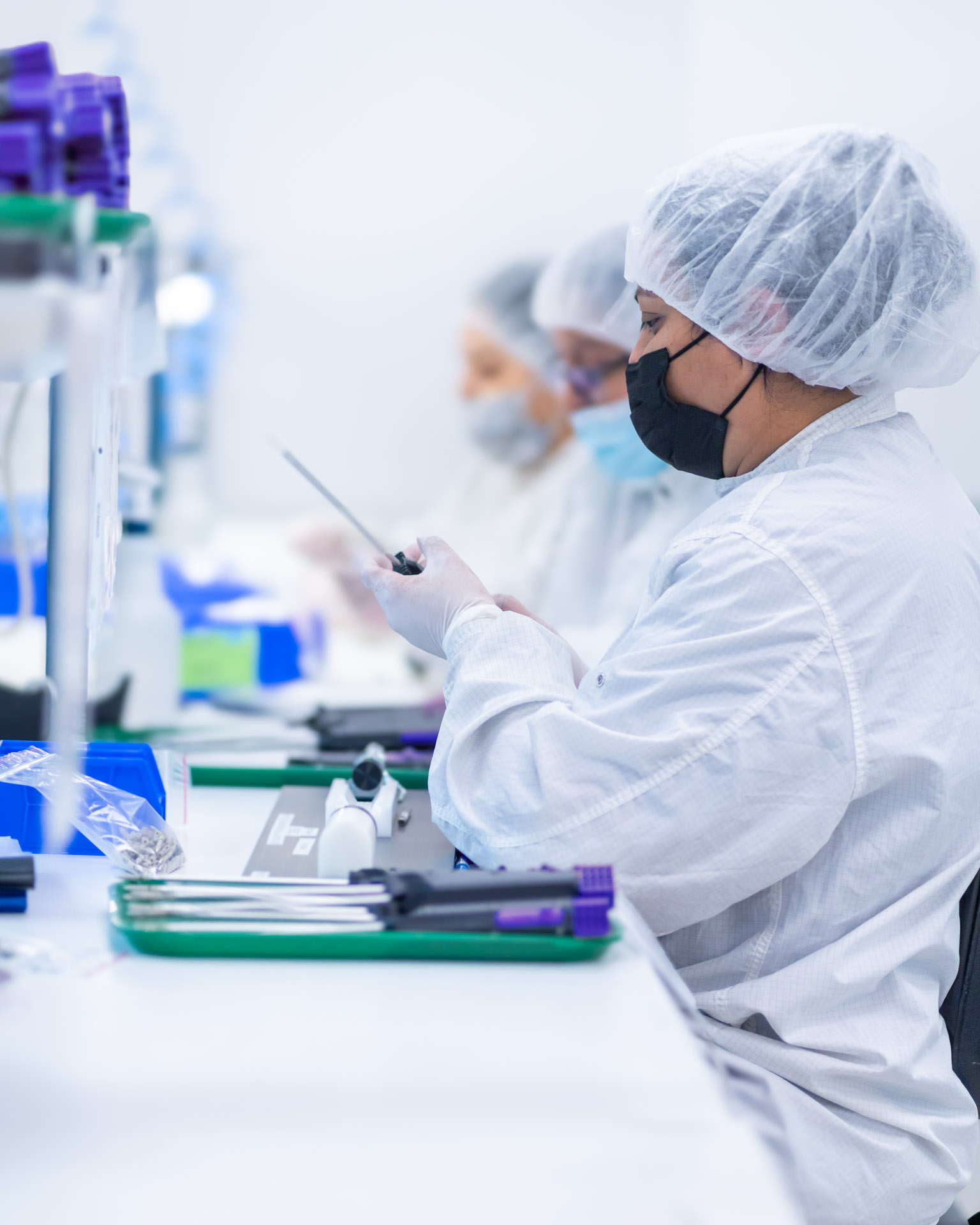 Technicians in cleanroom PPE assembling minimally invasive medical devices with precision and regulatory focus.