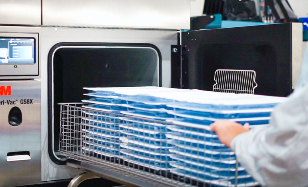 Technician loading medical device trays into 3M EO sterilization chamber